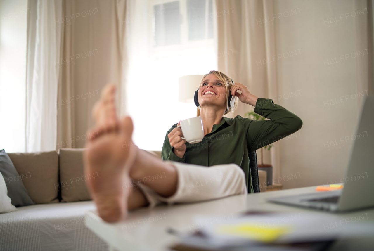 Portrait of happy business woman indoors in office sitting at desk, holding cup of tea.