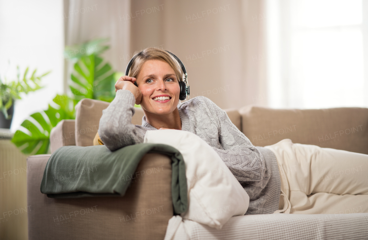 Top view portrait of woman with headphones relaxing indoors at home, mental health care concept.