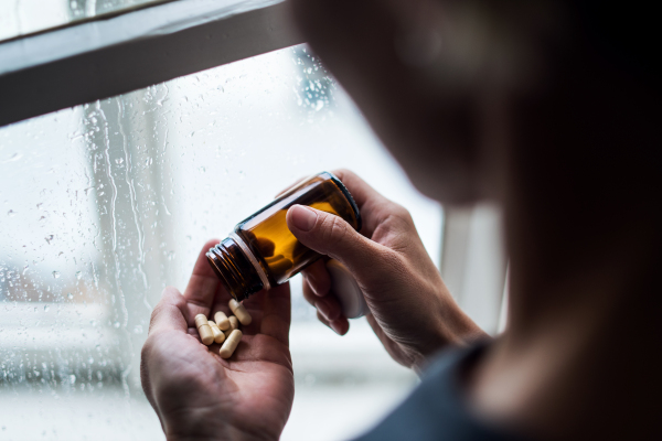 Depressed woman with pills indoors at home, mental health and drugs addiction concept.