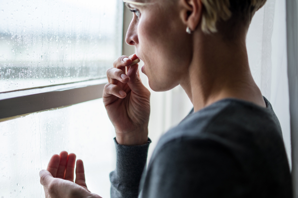 Depressed woman with pills indoors at home, mental health and drugs addiction concept.