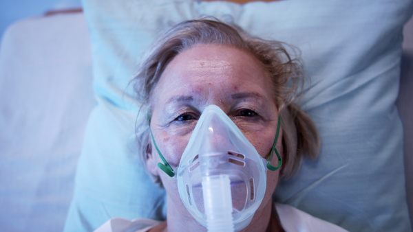 Top view of covid-19 infected patient with oxygen mask in bed in hospital, coronavirus and breathing problems concept.