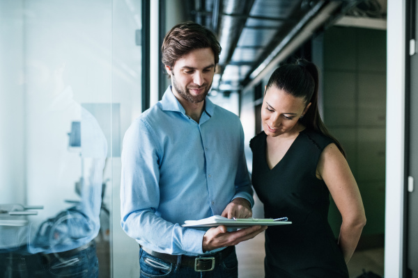 Young businesspeople with clipboard standing in an office, working.