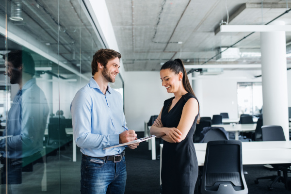 Young businesspeople with clipboard standing in an office, working.