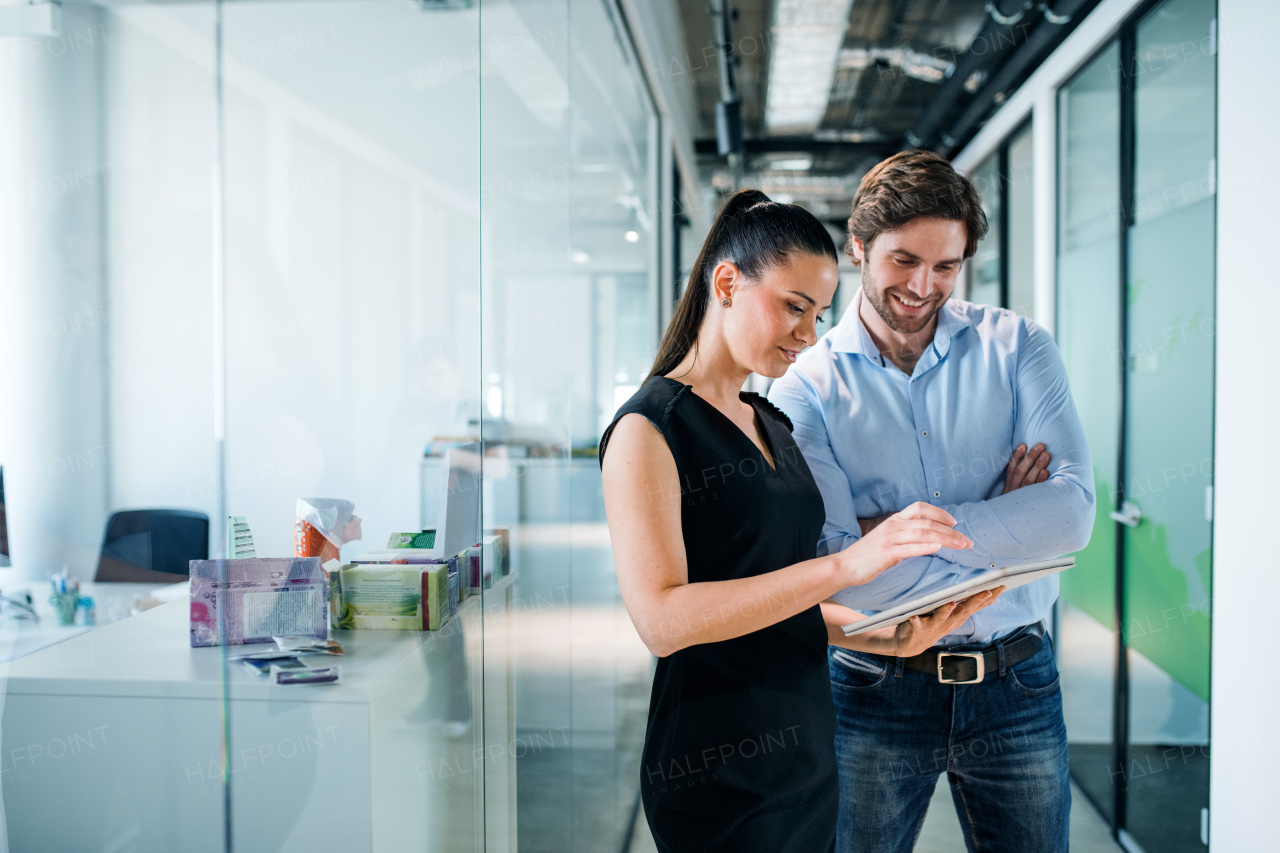 Young businesspeople with clipboard standing in an office, working.