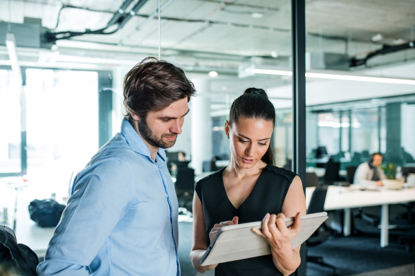 Young businesspeople with tablet standing in an office, working.