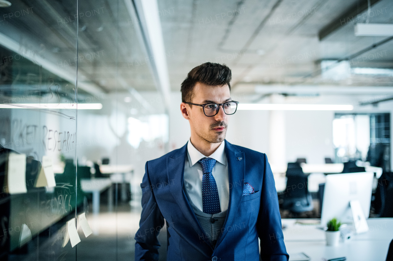 A portrait of young businessman walking in an office. Copy space.