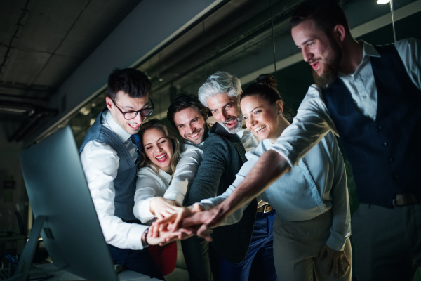 A group of business people with computer in an office in the evening, expressing excitement.