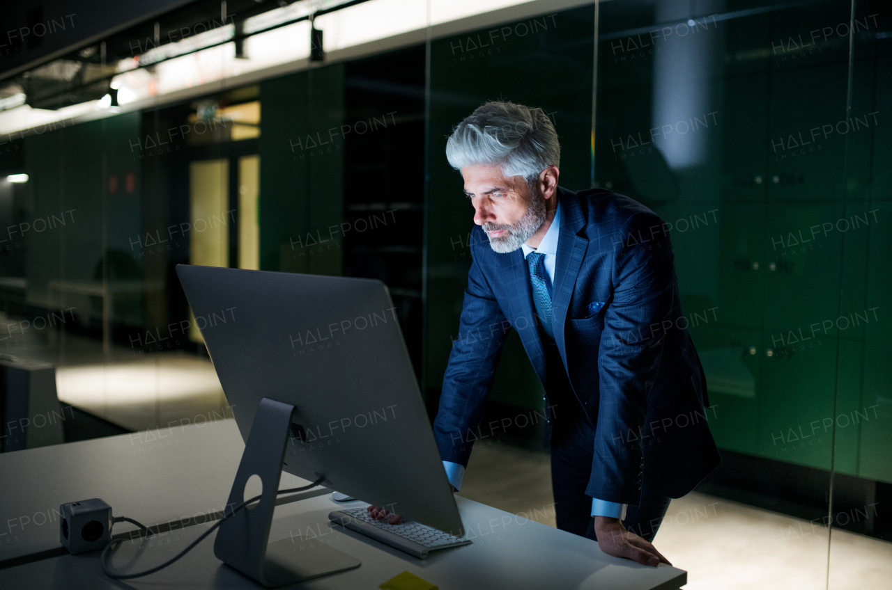 A portrait of mature businessman with computer in an office, working.