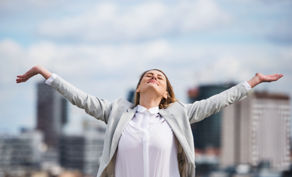 A young businesswoman standing on a terrace outside office, expressing excitement.