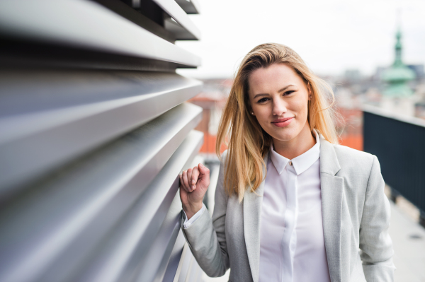 A portrait of young blond businesswoman standing outdoors.