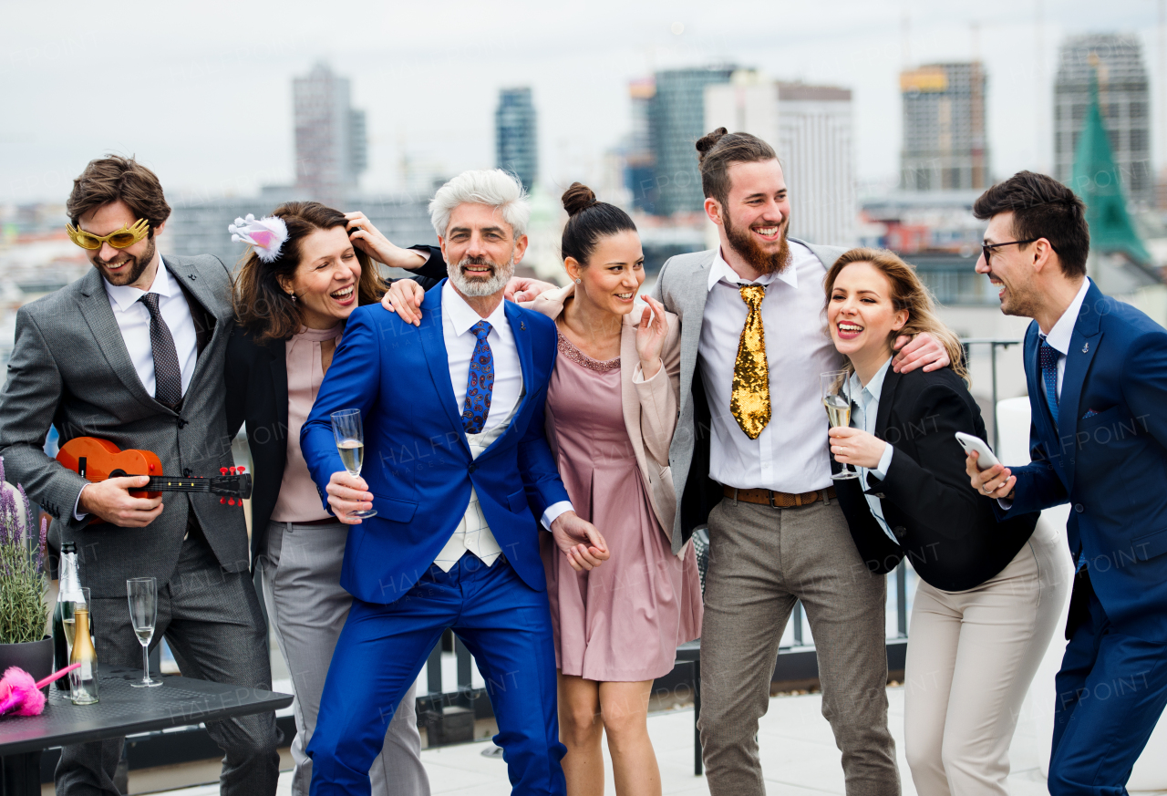 A large group of joyful businesspeople having a party outdoors on roof terrace in city.