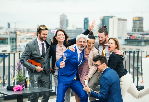 A large group of joyful businesspeople having a party outdoors on roof terrace in city.