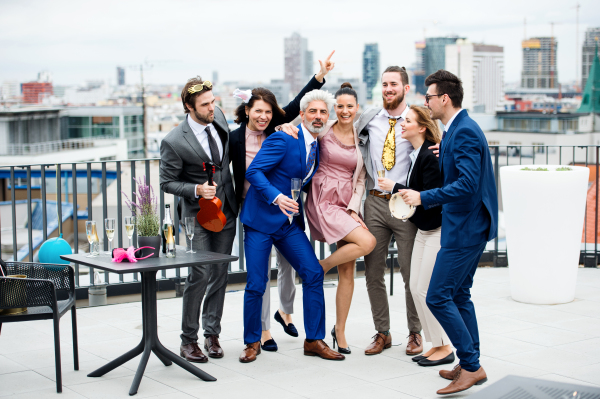 A large group of joyful businesspeople having a party outdoors on roof terrace in city.