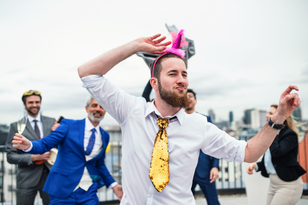 A large group of joyful businesspeople having a party outdoors on roof terrace in city.