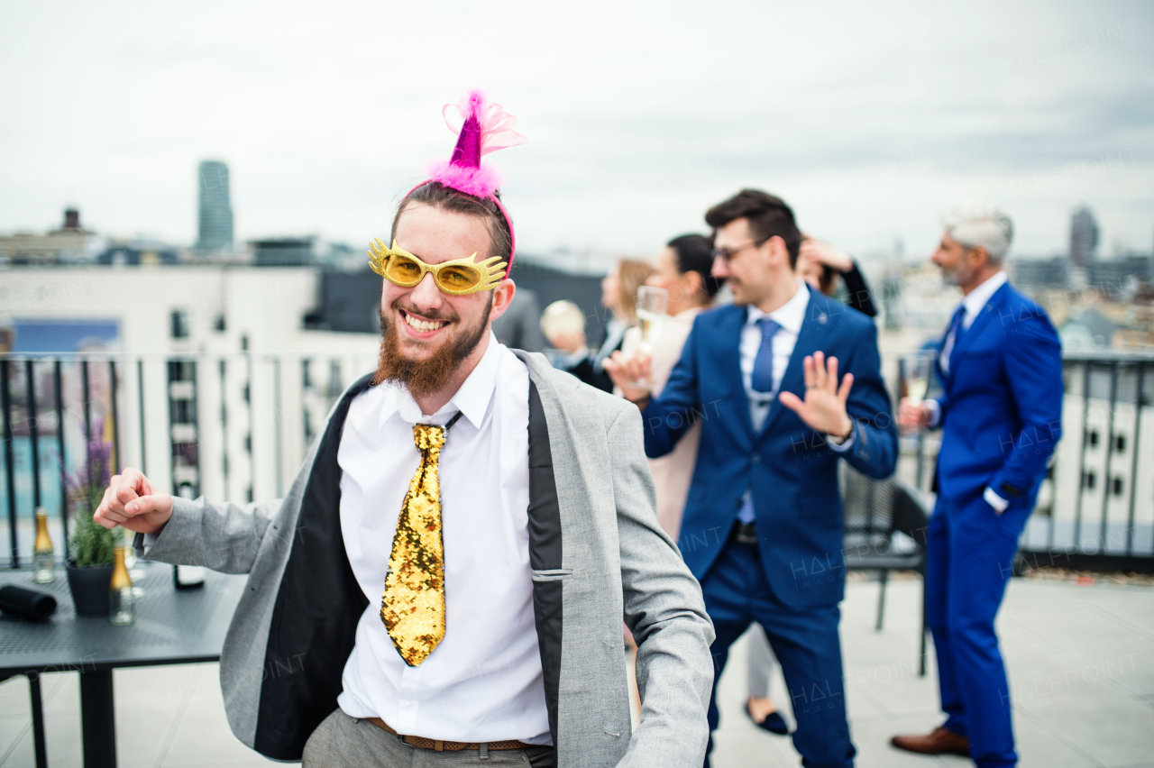 A large group of joyful businesspeople having a party outdoors on roof terrace in city.