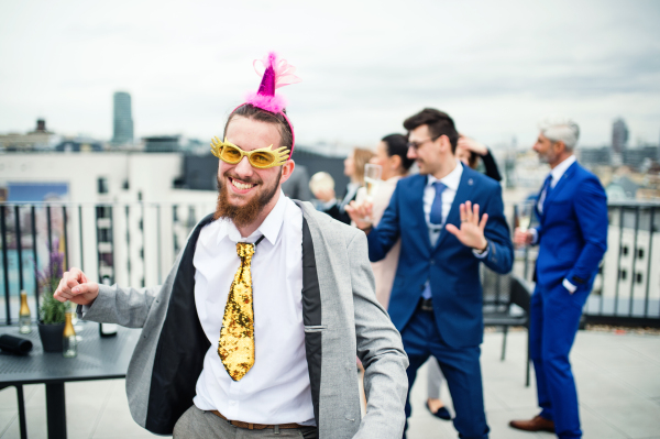 A large group of joyful businesspeople having a party outdoors on roof terrace in city.