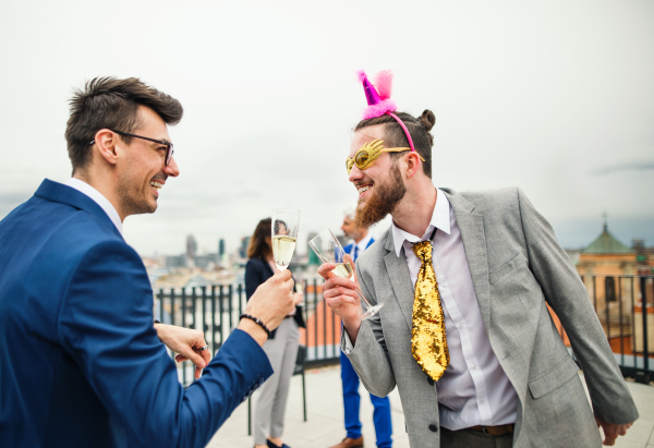 A large group of joyful businesspeople having a party outdoors on roof terrace in city.