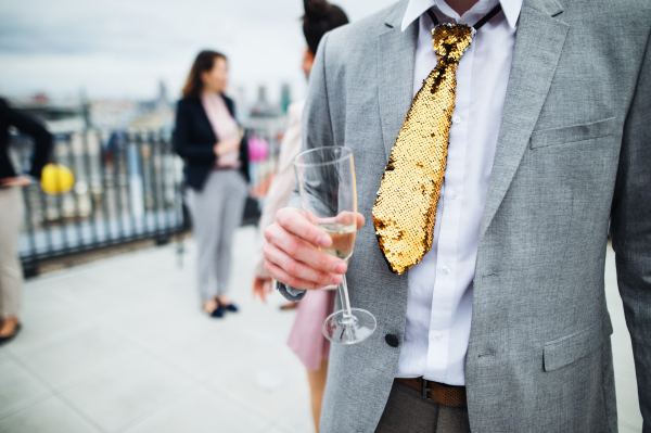 A large group of joyful businesspeople having a party outdoors on roof terrace in city, midsection.