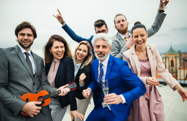 A large group of joyful businesspeople having a party outdoors on roof terrace in city.