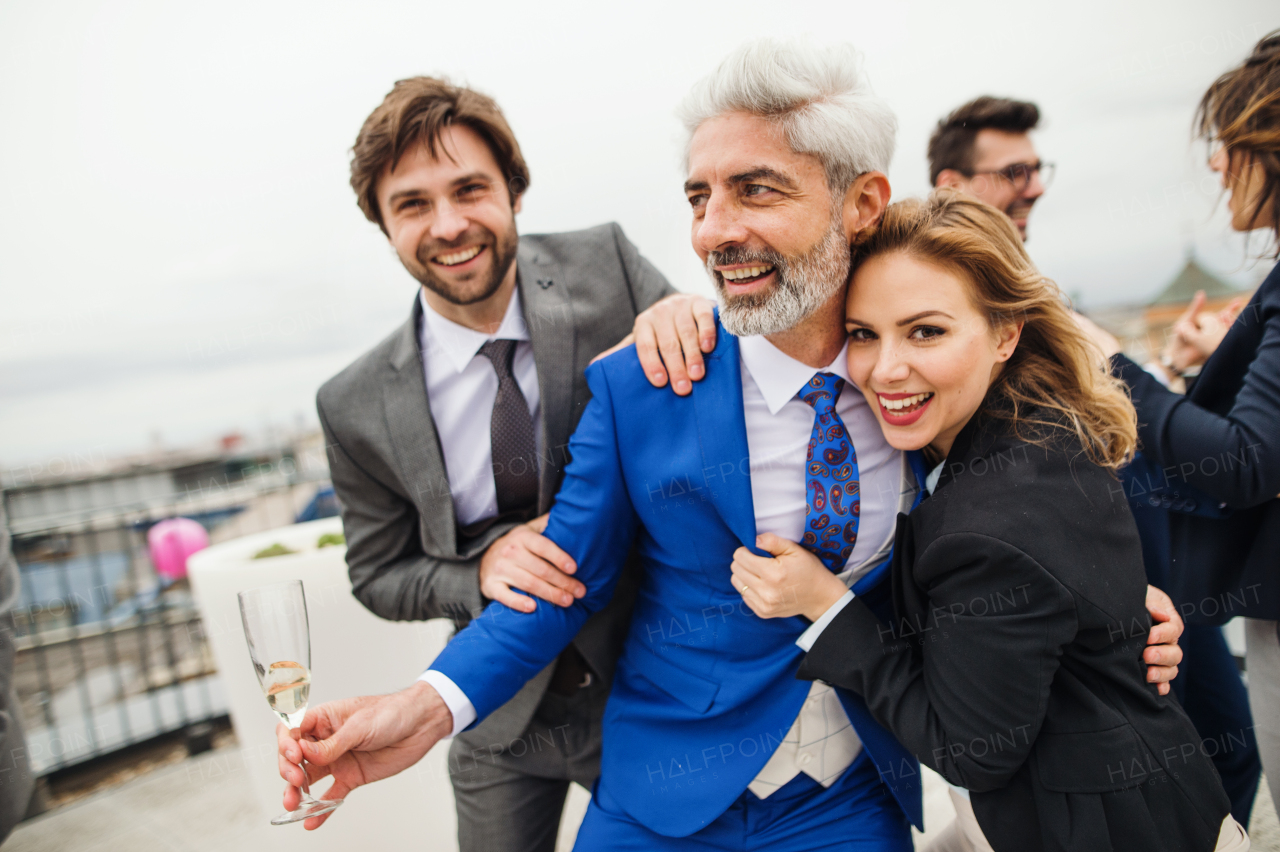 A large group of joyful businesspeople having a party outdoors on roof terrace in city.