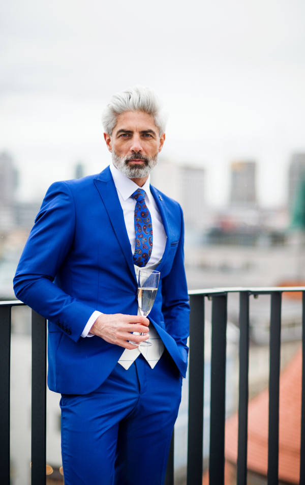 A mature businessman with champagne in glass having a party outdoors on roof terrace in city.