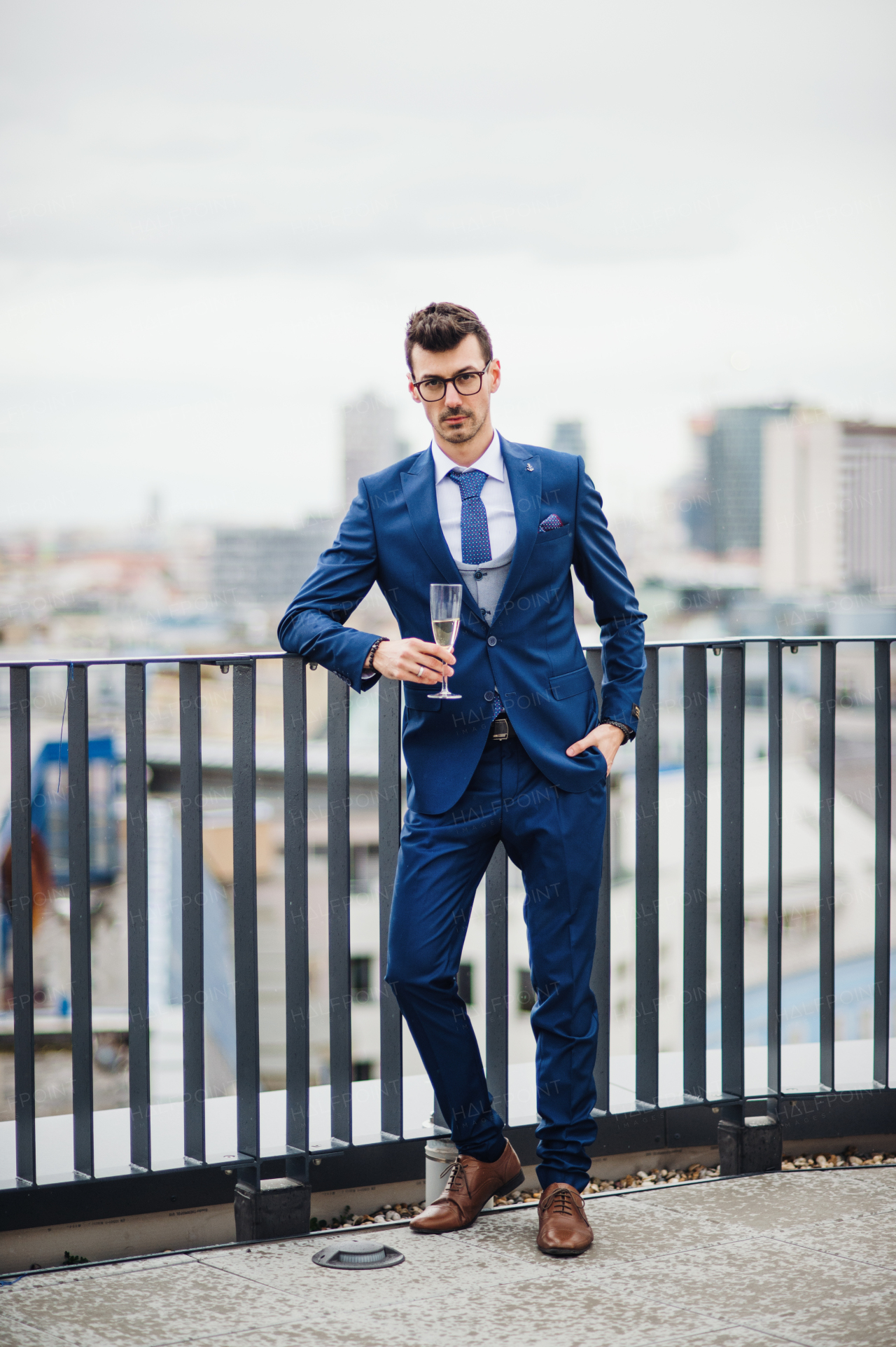 A young businessman with champagne in glass on a party outdoors on roof terrace in city.