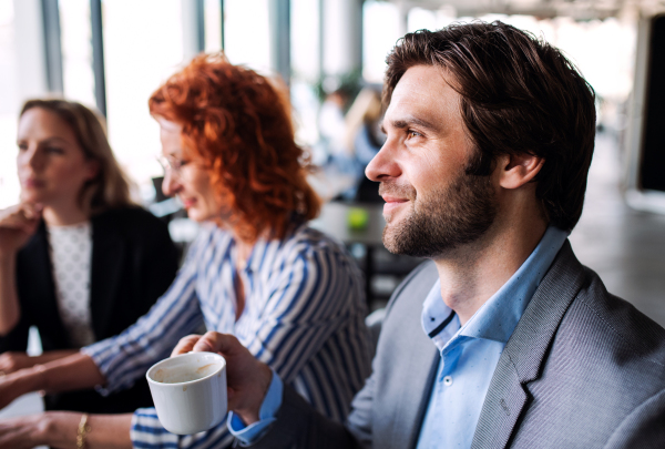 A group of young cheerful business people sitting in an office, working.