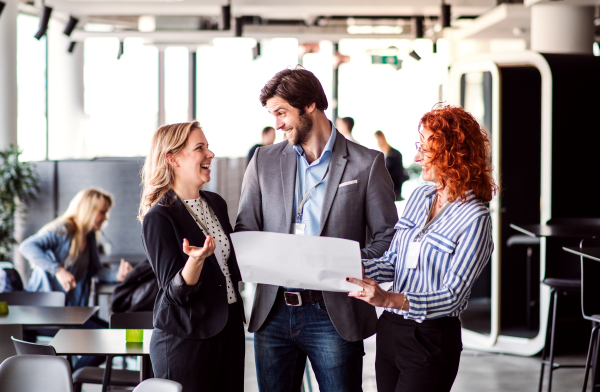 A group of cheerful business people with documents standing in an office, expressing excitement.