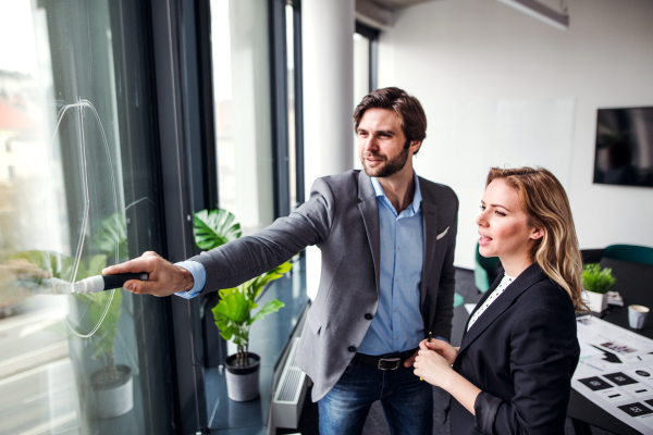 Two young business people talking in an office, brainstorming.