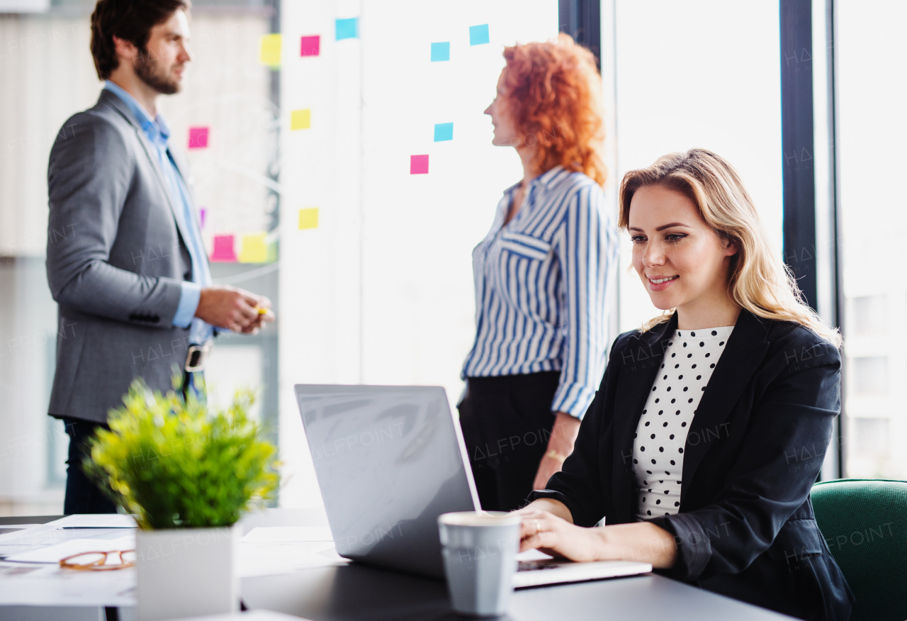 A group of young business people sitting and talking in an office, working.