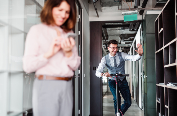 Young businessman with motor scooter in an office building, taking a break.