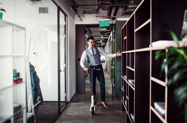 Young businessman with motor scooter in an office building, taking a break.