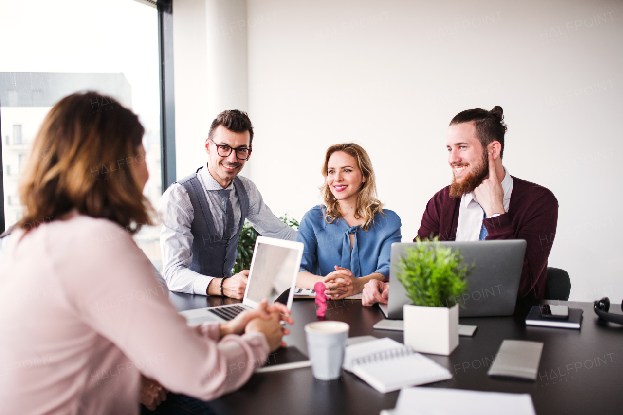 A group of young business people sitting and talking in an office, having meeting.