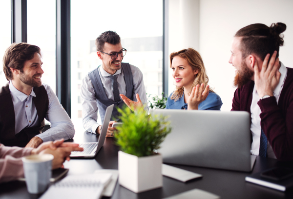 A group of young business people sitting and talking in an office, having meeting.