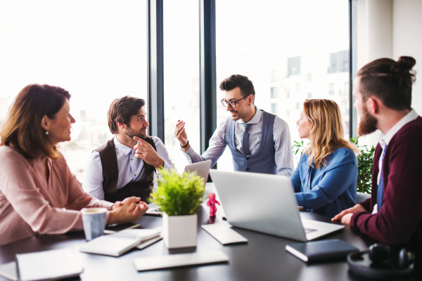 A group of young business people sitting and talking in an office, having meeting.