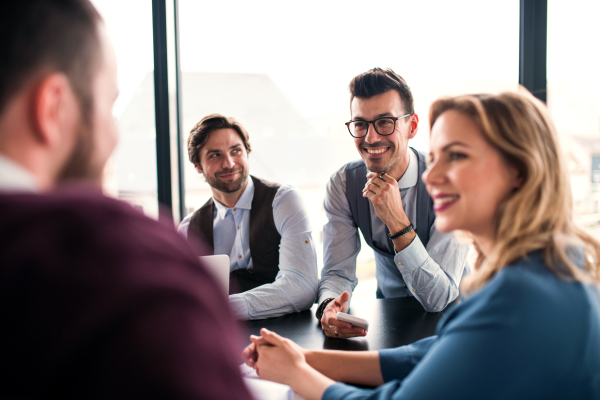 A group of young business people sitting and talking in an office, having meeting.