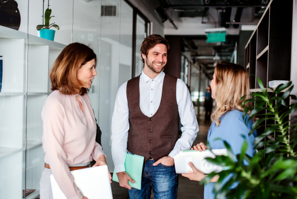 A group of business people standing in an office building, talking.