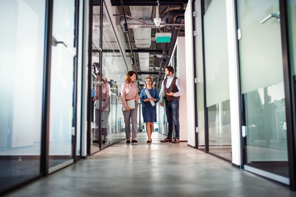 A group of business people walking in corridor office building, talking.