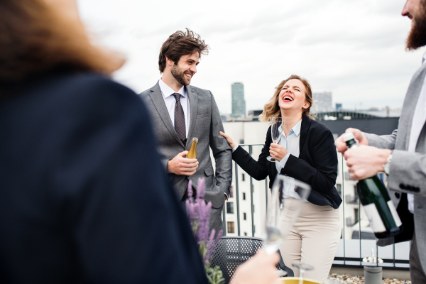 A large group of joyful businesspeople having a party outdoors on roof terrace in city.