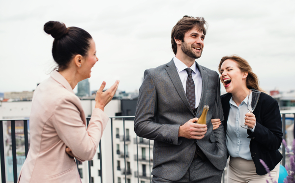 A large group of joyful businesspeople having a party outdoors on roof terrace in city.