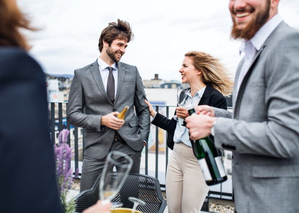 A midsection of group of joyful businesspeople having a party outdoors on roof terrace in city.