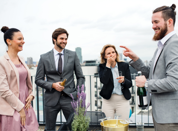 A large group of joyful businesspeople having a party outdoors on roof terrace in city.