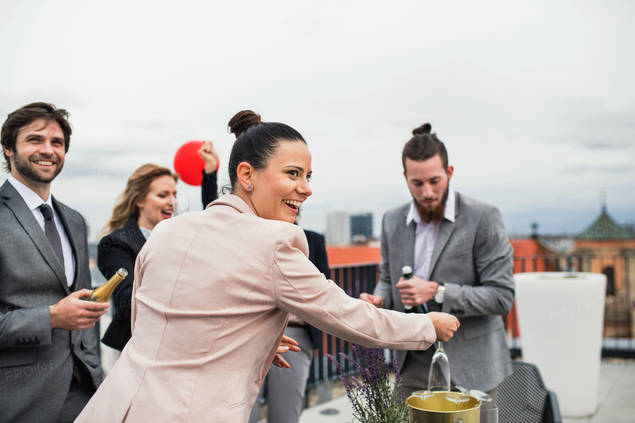 A large group of joyful businesspeople having a party outdoors on roof terrace in city.