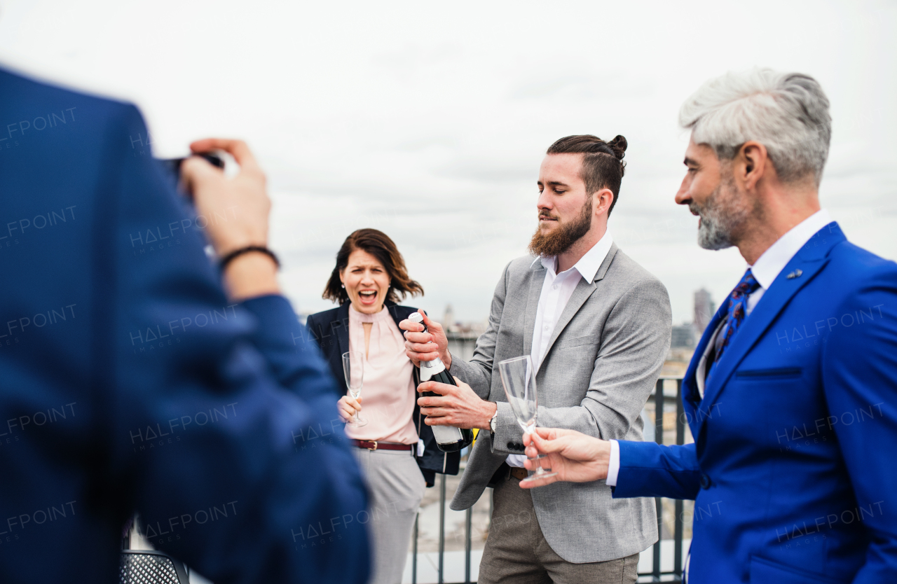 A large group of joyful businesspeople having a party outdoors on roof terrace in city.