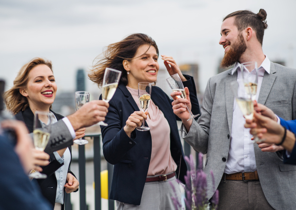 A large group of joyful businesspeople having a party outdoors on roof terrace in city.