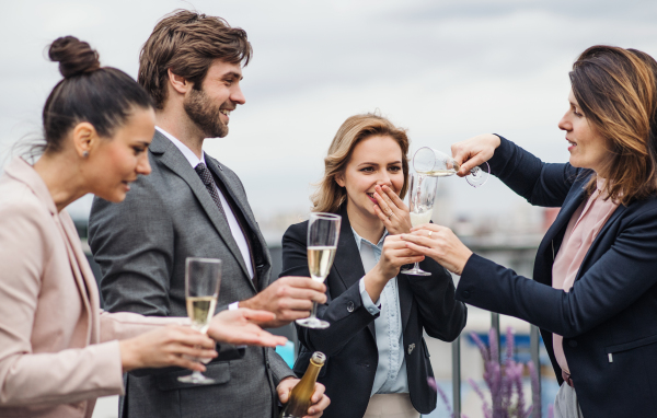 A large group of joyful businesspeople having a party outdoors on roof terrace in city.