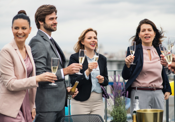 A large group of joyful businesspeople having a party outdoors on roof terrace in city.