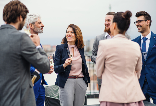 A large group of joyful businesspeople having a party outdoors on roof terrace in city.