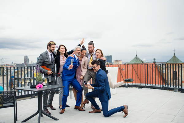 A large group of joyful businesspeople having a party outdoors on roof terrace in city.