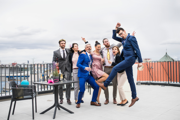 A large group of joyful businesspeople having a party outdoors on roof terrace in city.